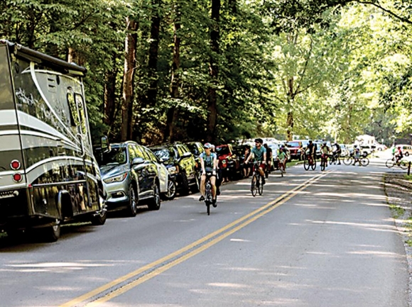 Cyclists pedal past full roadside parking areas. NPS photo