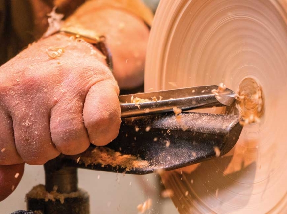  Mike McKinney resumes turning on a partially carved bowl he plucked from a shelf.  He said he puts about three hours of work into each bowl, but most will dry for about a year during the process. 