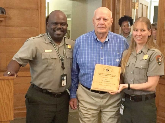Jim Goddard (center) is presented with a plaque recognizing his accomplishments from Park Superintendent Cassius Cash and Backcountry Specialist Christine Hoyer. NPS photo