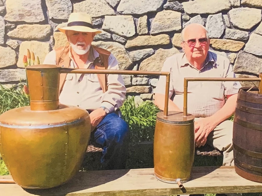 Charles Miller (left) sits with longtime friend Earl Lanning behind a non-working still Miller built for Western Carolina University some years ago. Donated photo