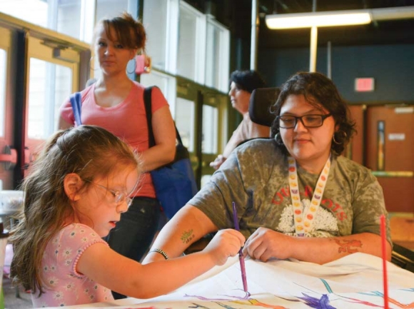 Ladybug Bone, 6, adds a few strokes to a painting created at the Rally for Recovery. The piece will be displayed at the Analenisgi Recovery Center. Holly Kays photo