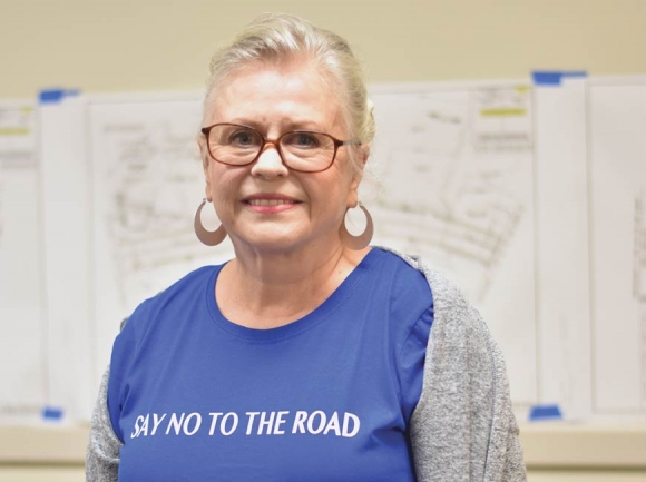 Jeannie Kelley stands in front of preliminary N.C. 107 plans sporting her ‘Say No To The Road’ apparel. Holly Kays photo