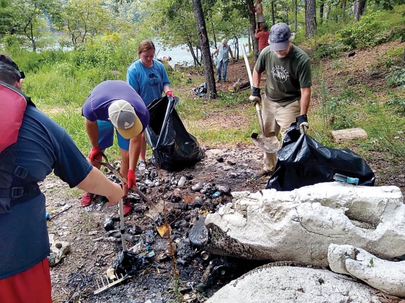 Volunteers work to clean up a trashed campsite. Donated photo