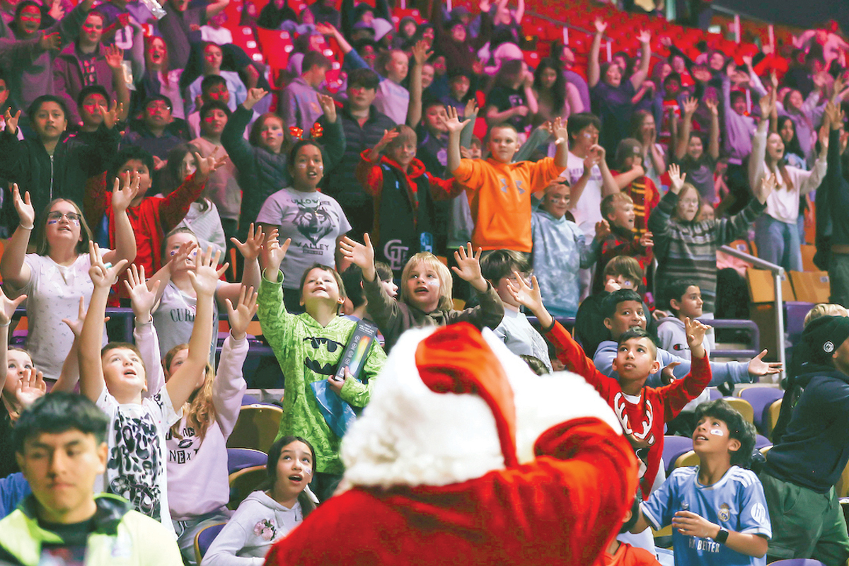Santa tosses candy canes to the excited crowd of students. 
