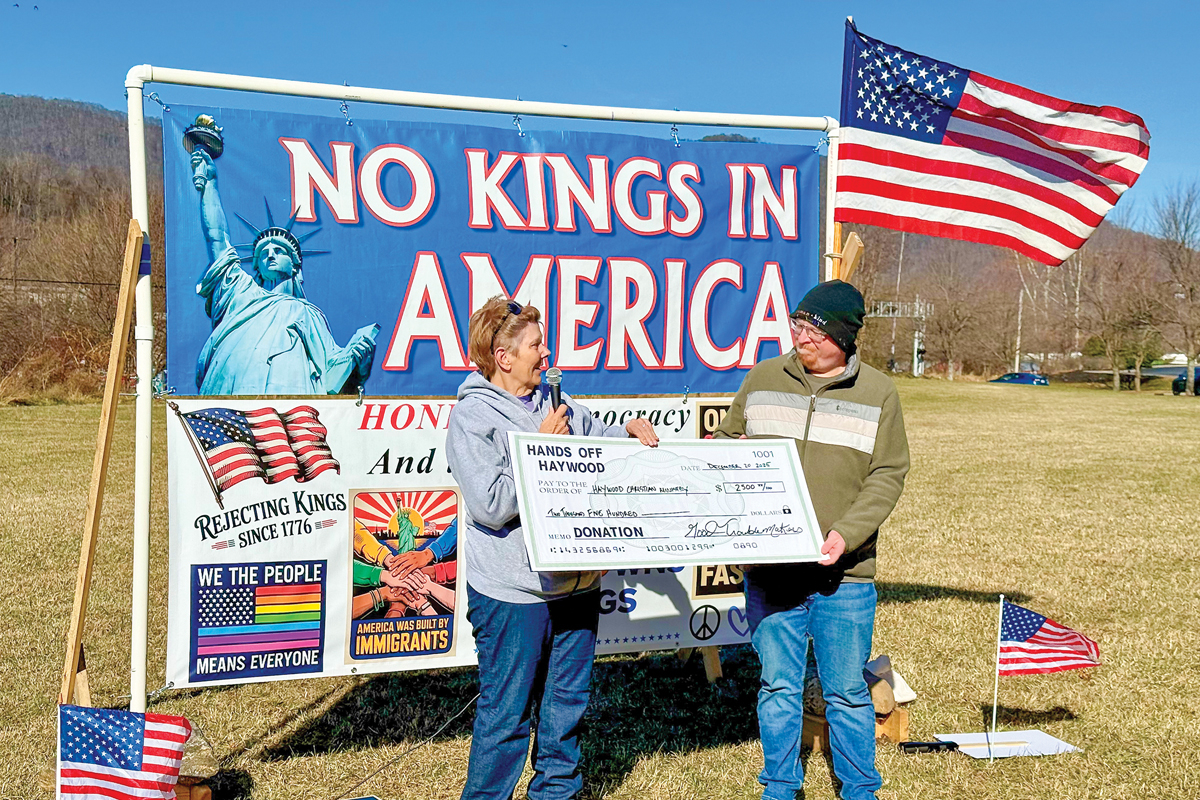 Hands off Haywood organizer Mary Ford (right) presents a check to Blake Hart of Haywood Christian Ministry. 