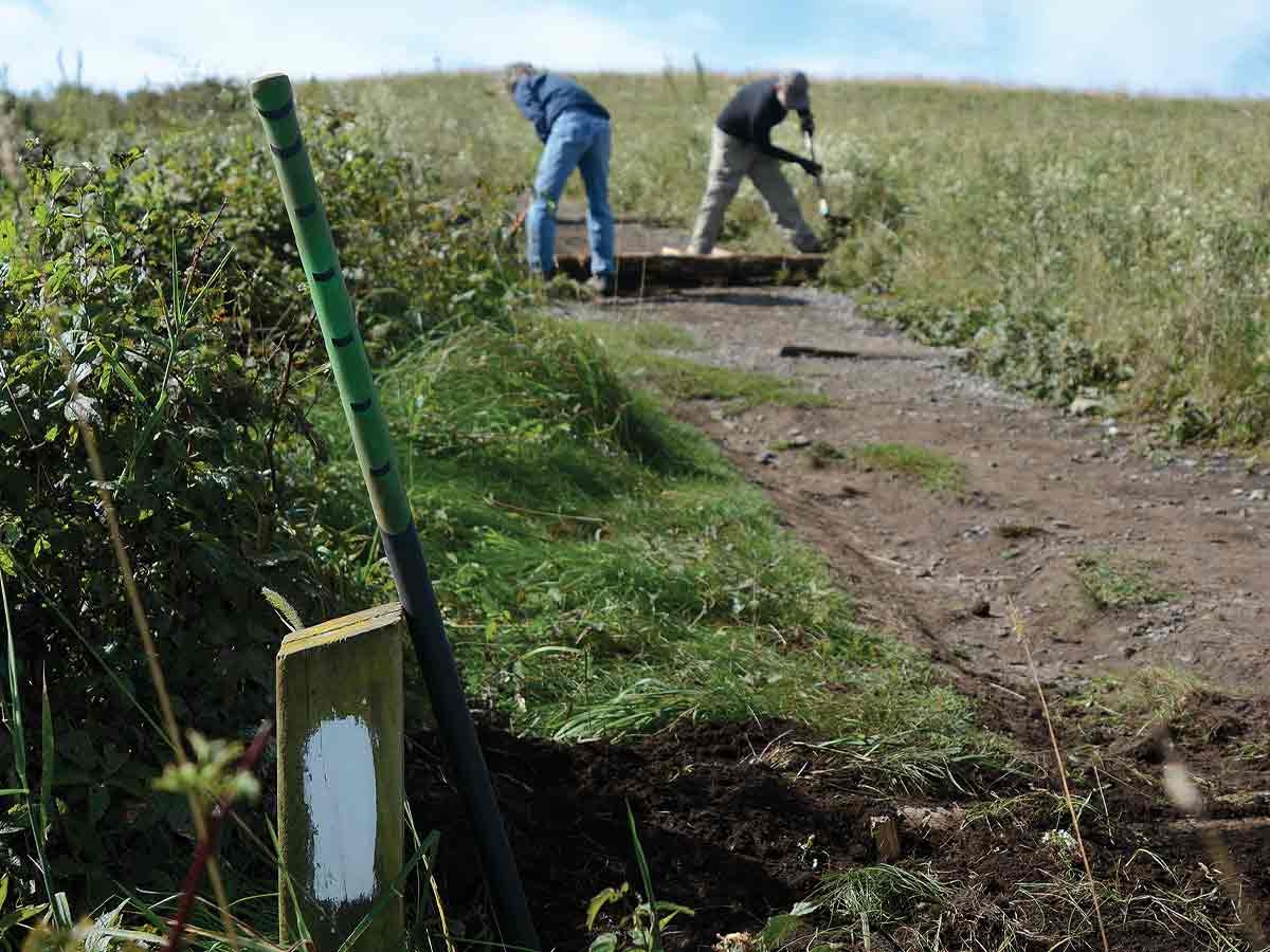 Mike Wurman and Scott Varn work to install a locust log water bar on the Appalachian Trail at Max Patch during a Sept. 25 volunteer work day. Holly Kays photo