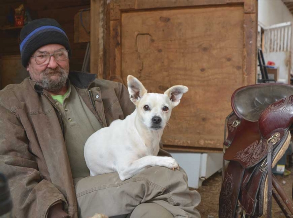 Weeping Cherry Stables operator James Lunsford sits in his barn with one of his dogs, Powder. Cory Vaillancourt photo