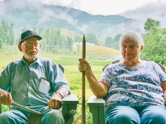 Ben Best (left) sits on the porch with wife Clarine, who’s holding a spike of the sort used for tobacco harvesting. Cory Vaillancourt photo.