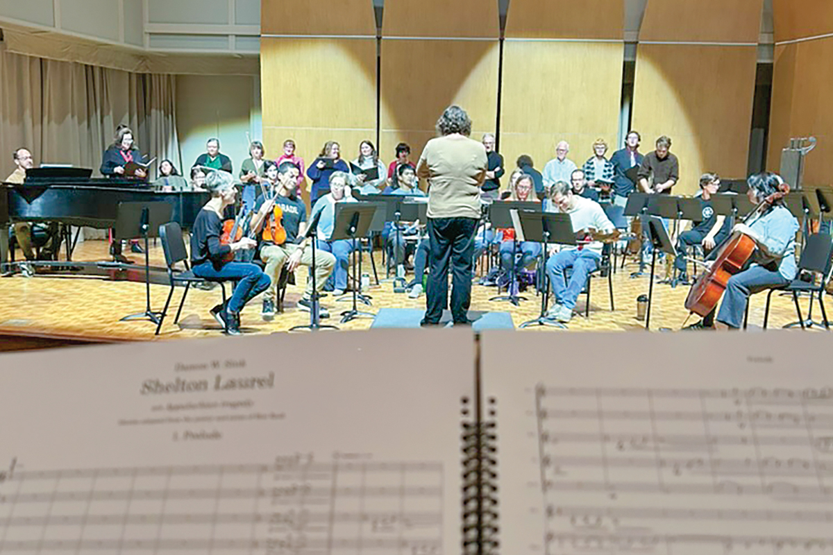 The libretto for Shelton Laurel sits in the foreground as performers rehearse. 