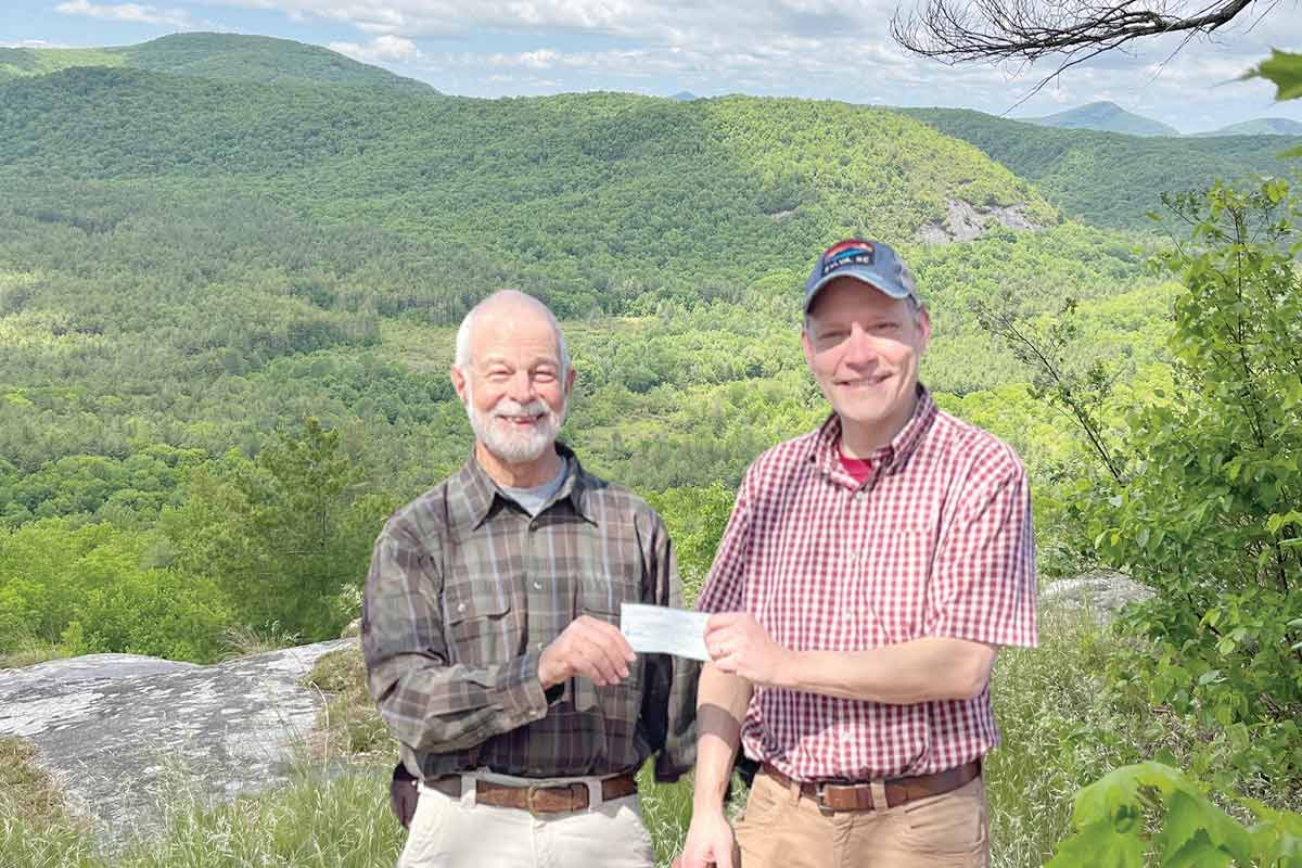 Burt Kornegay (left) hands off the donation to Friends of Panthertown Executive Director Jason Kimenker. 