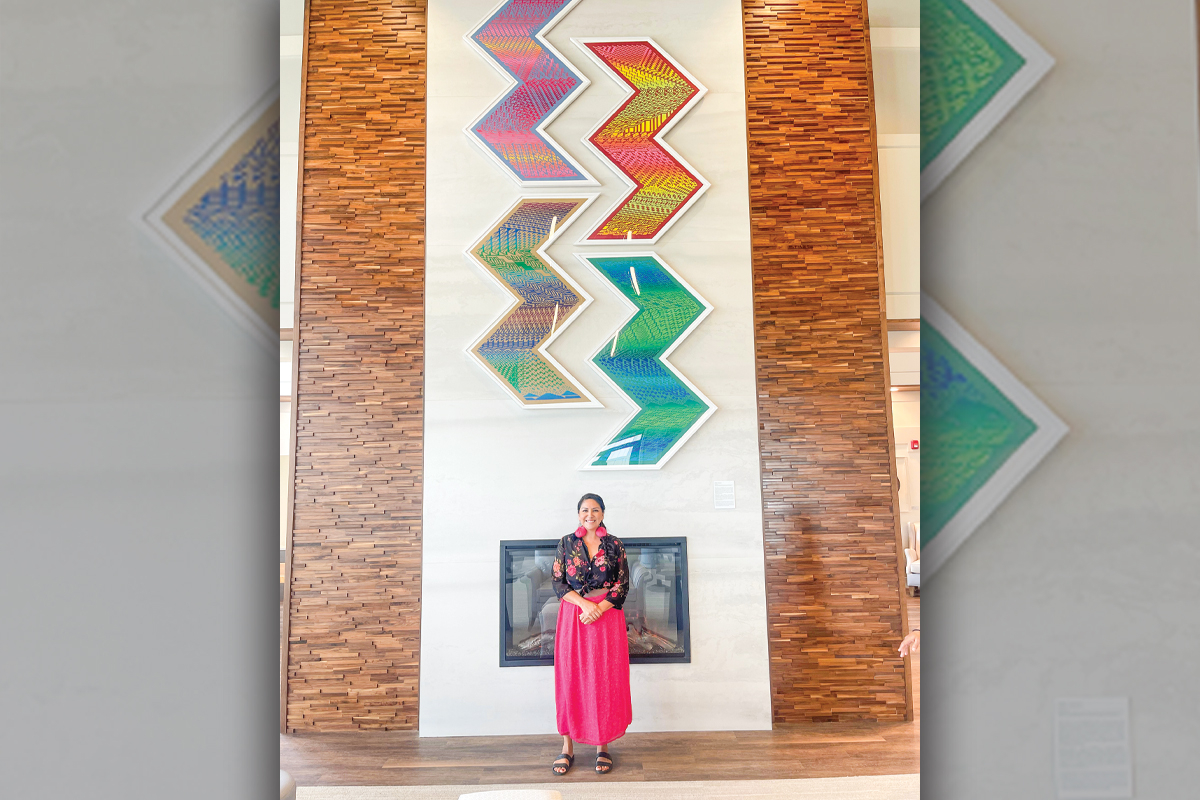 Rhiannon Skye Tafoya stands in front of her commissioned pieces at the Tsali Care Center, a senior care facility in Cherokee that opened last year.