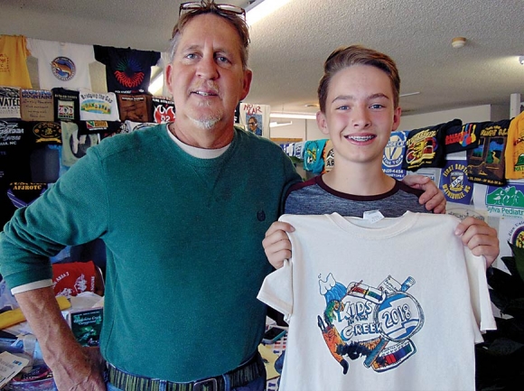 Rick Thomas (left) and Lucas Cody show off winning design for this year’s  Kids in the Creek T-shirt. Donated photo