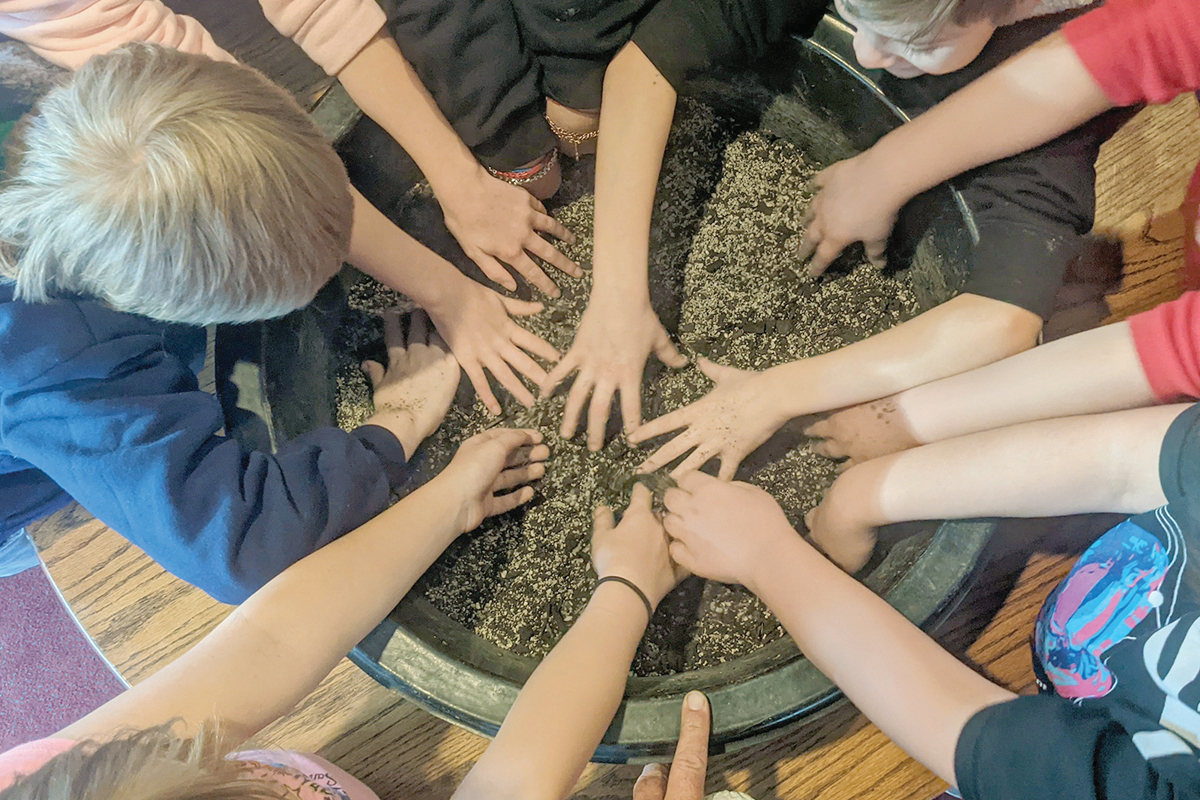 Kids put their hands in to mix up seed bombs. Adam Bigelow photo