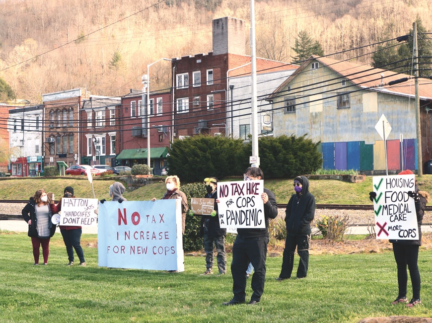 Protestors hold signs opposing a plan to increase taxes to fund additional police officers during a public hearing on a different topic the board held at Bridge Park April 1. Holly Kays photo