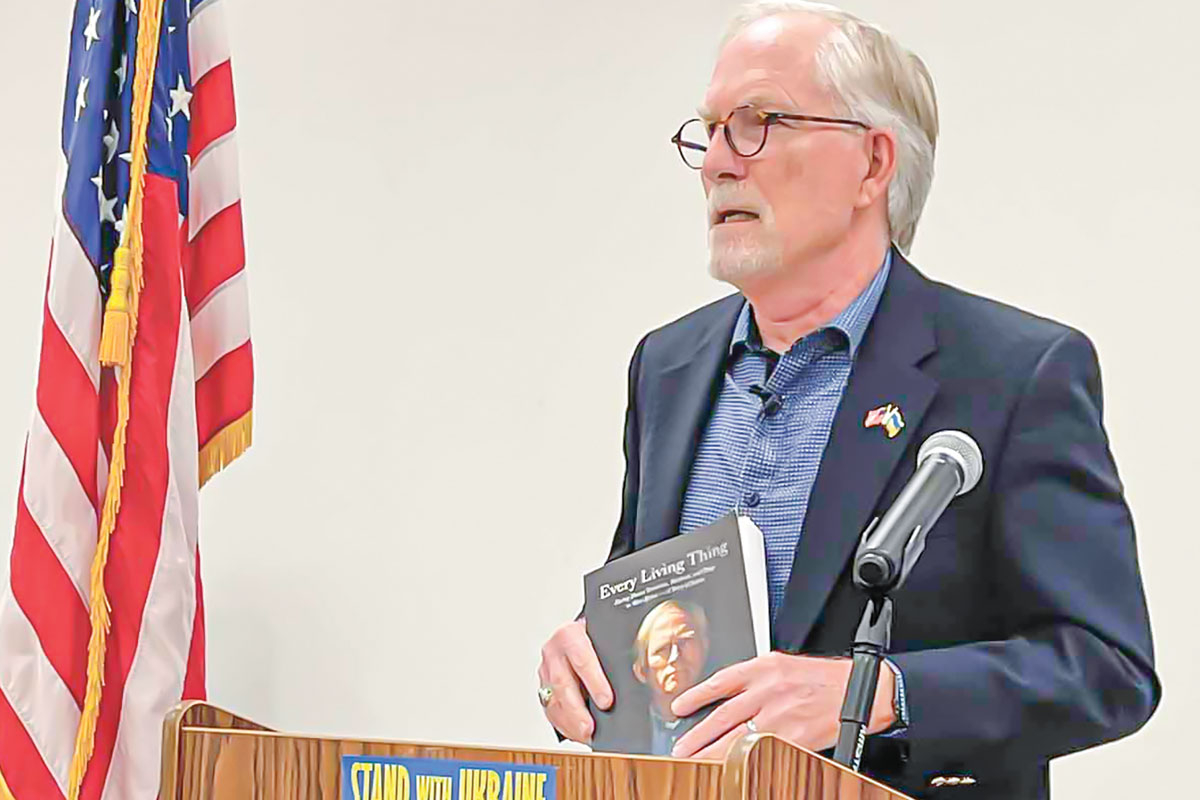 David Crane holds up a copy of his book, ‘Every Living Thing: Facing Down Terrorists, Warlords, and Thugs in West Africa — A Story of Justice.’ Kyle Perrotti photo