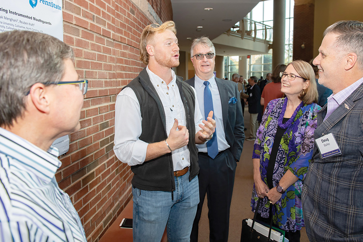 Engineering professor Martin Tanaka (left) and graduate student Clayton Bardall  discuss their mouthguard research at WCU’s Scholarship Showcase. Donated photo