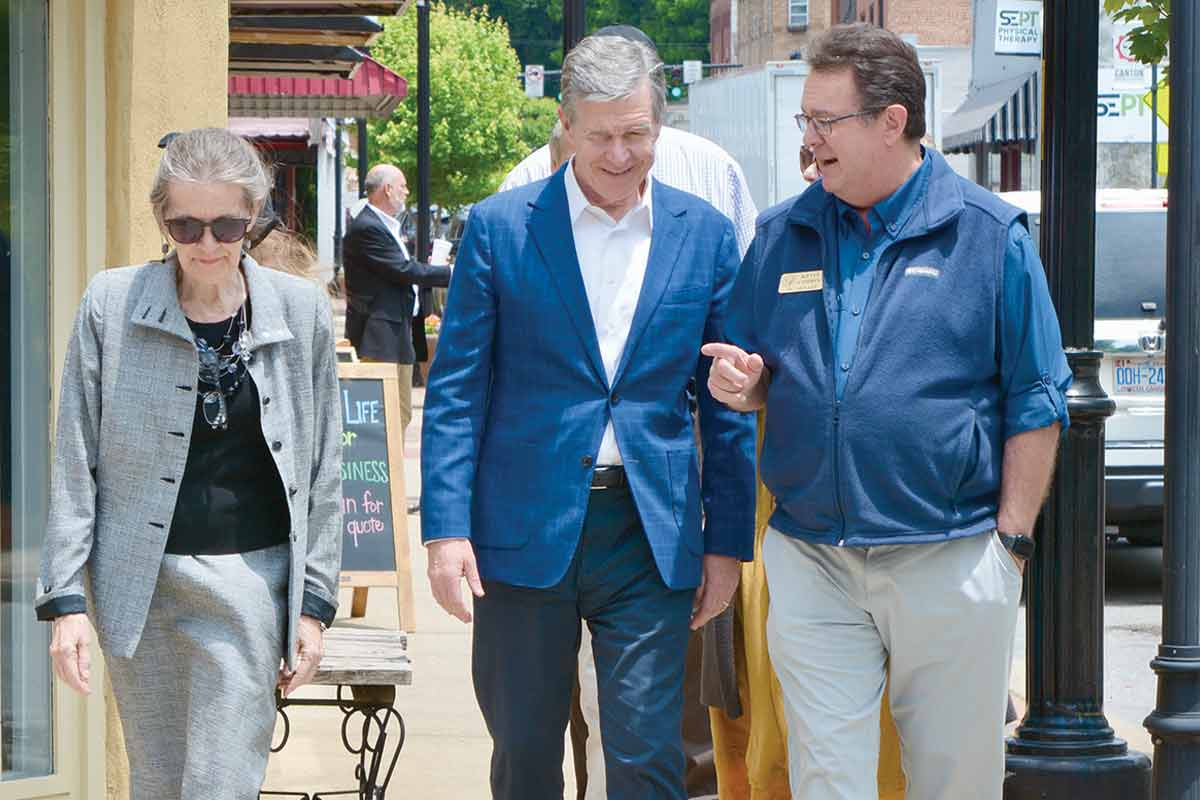 Gov. Roy Cooper (center) walks down Canton&#039;s Main Street with Mayor Pro Tem Gail Mull and Sen. Kevin Corbin on May 26.