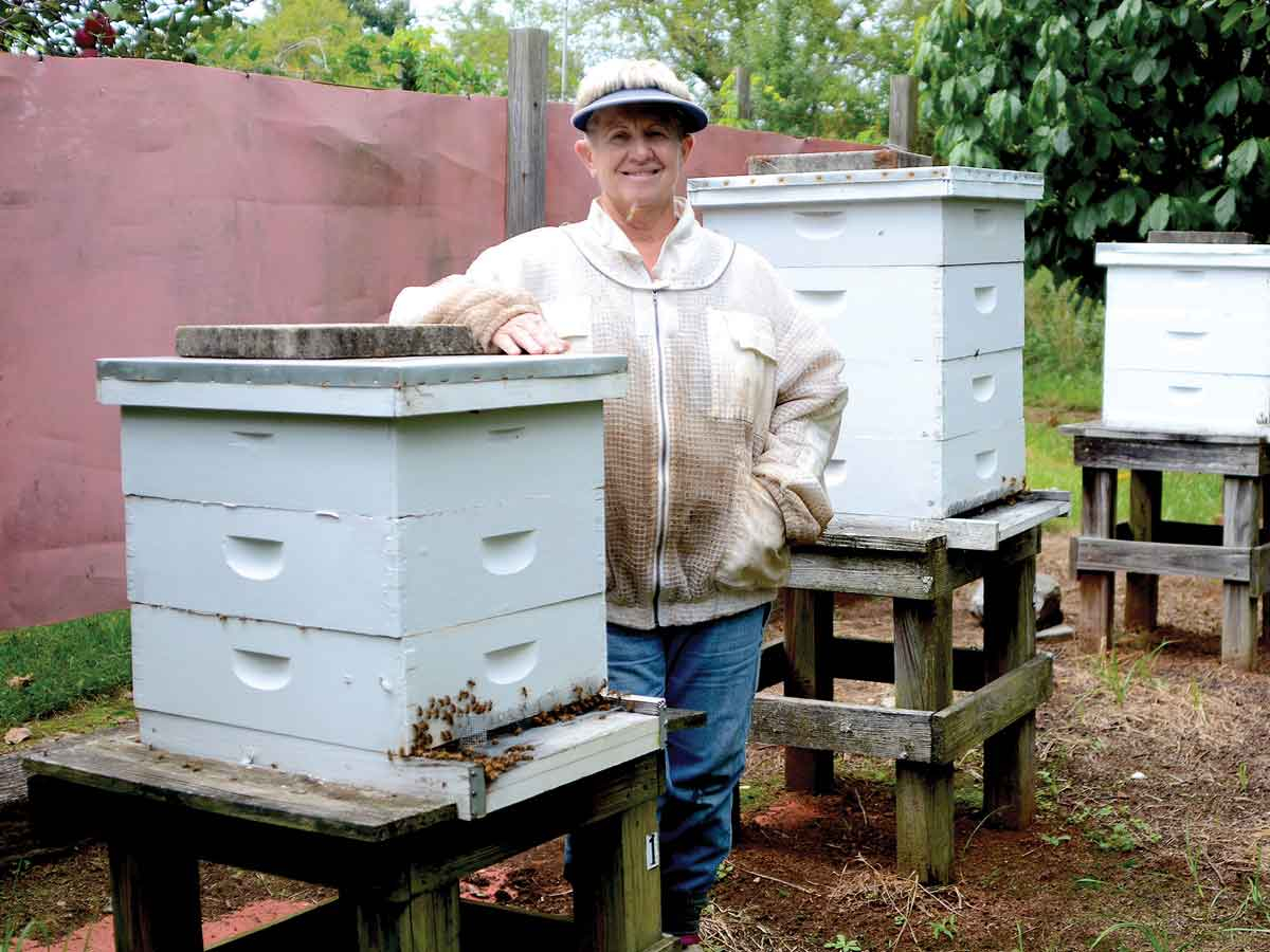 Kathy “KT” Taylor stands with her bees, which provide critical pollination during apple blossom season. Holly Kays photo