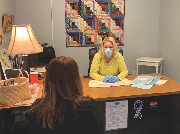 Julia Freeman, executive director of REACH of Haywood County, assists a client while wearing a face mask to prevent potential spread of COVID-19. Donated photo