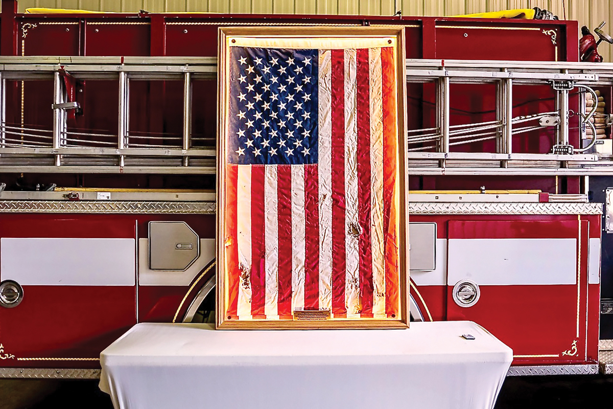 A storm-damaged American flag, recovered from the Rocky Broad River after Hurricane Helene, is displayed in a Chimney Rock firehouse following its restoration and framing. 