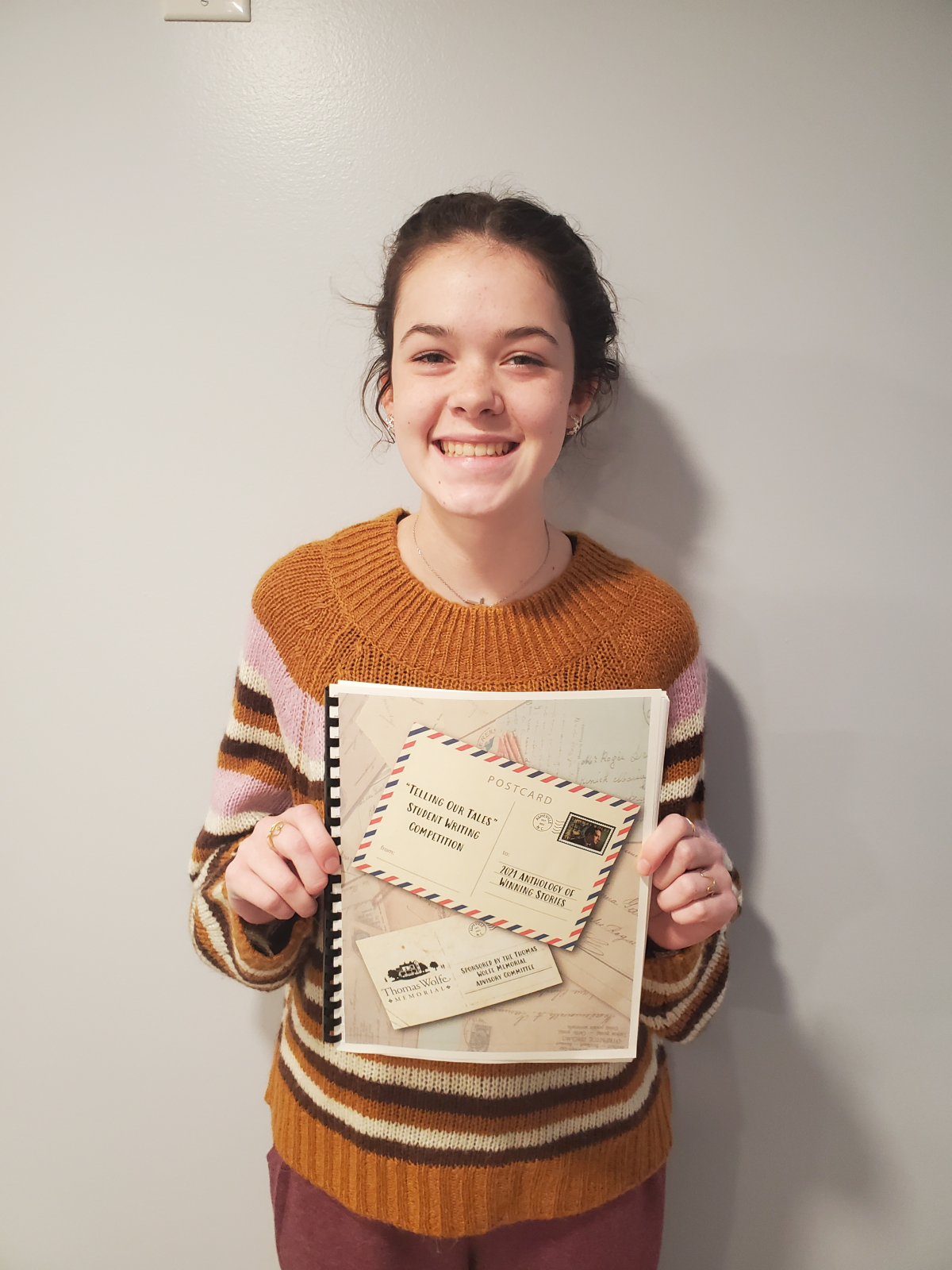 Eireann Marcus, a ninth grader at Tuscola High School, won 1st place in the high school division of the Thomas Wolfe Memorial’s annual “Telling our Tales” Student Writing Competition. She is holding the 2021 Anthology of Winning Stories of the Thomas Wolfe Memorial’s writing contest where her story is featured. 