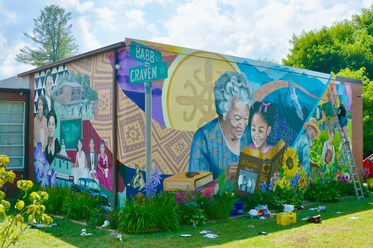 Muralist Kristy McCarthy (far right) puts the finishing touches on her mural at the Pigeon Community Multicultural Development Center on June 28, 2024. Cory Vaillancourt photo