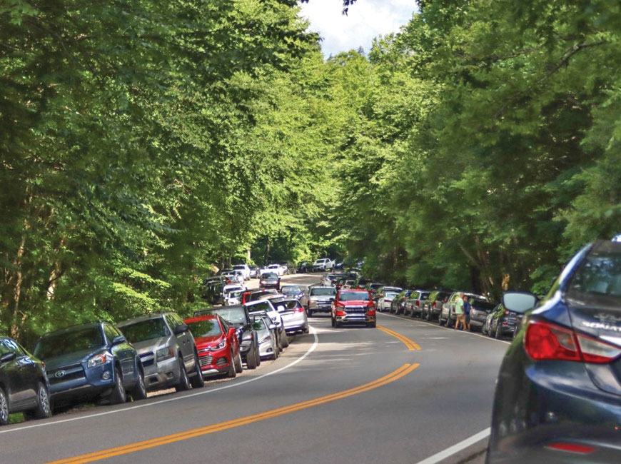 On a Saturday in July 2020, cars line both sides of Newfound Gap Road near the trailhead for Alum Cave Trail. NPS photo