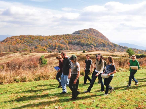 Susan Sachs leads a group of students across the lawn at Purchase Knob. GSMA photo