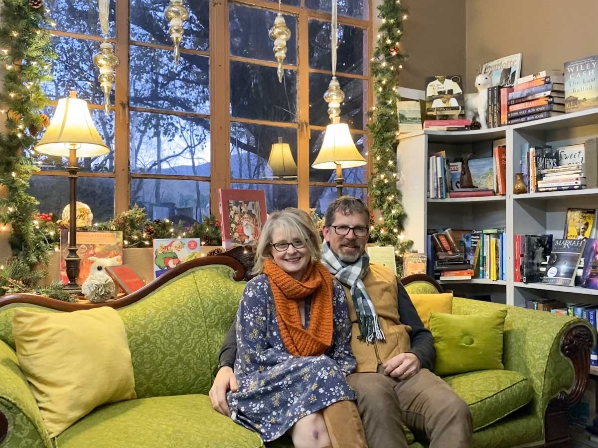 Greg and Bonnie Owens sit on Miss Virginia, in front of the window of Wall Street Books. 