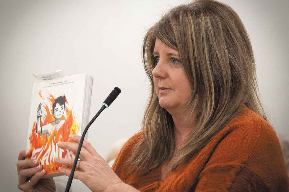 A speaker holds up a book containing LGBTQ content during public comment at a March 14 Macon County Commission meeting. Bob Scott photo