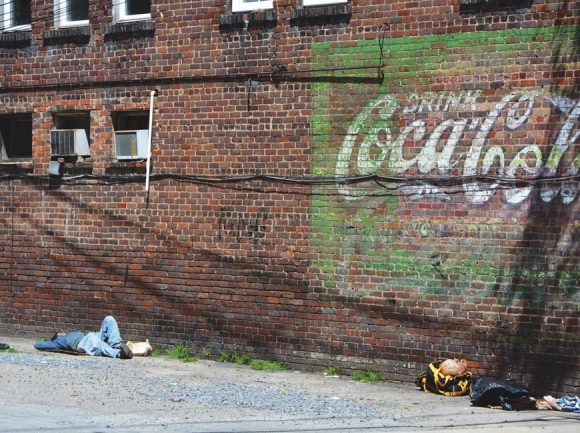 A man naps outside a building in Waynesville&#039;s Frog Level district in late 2019.