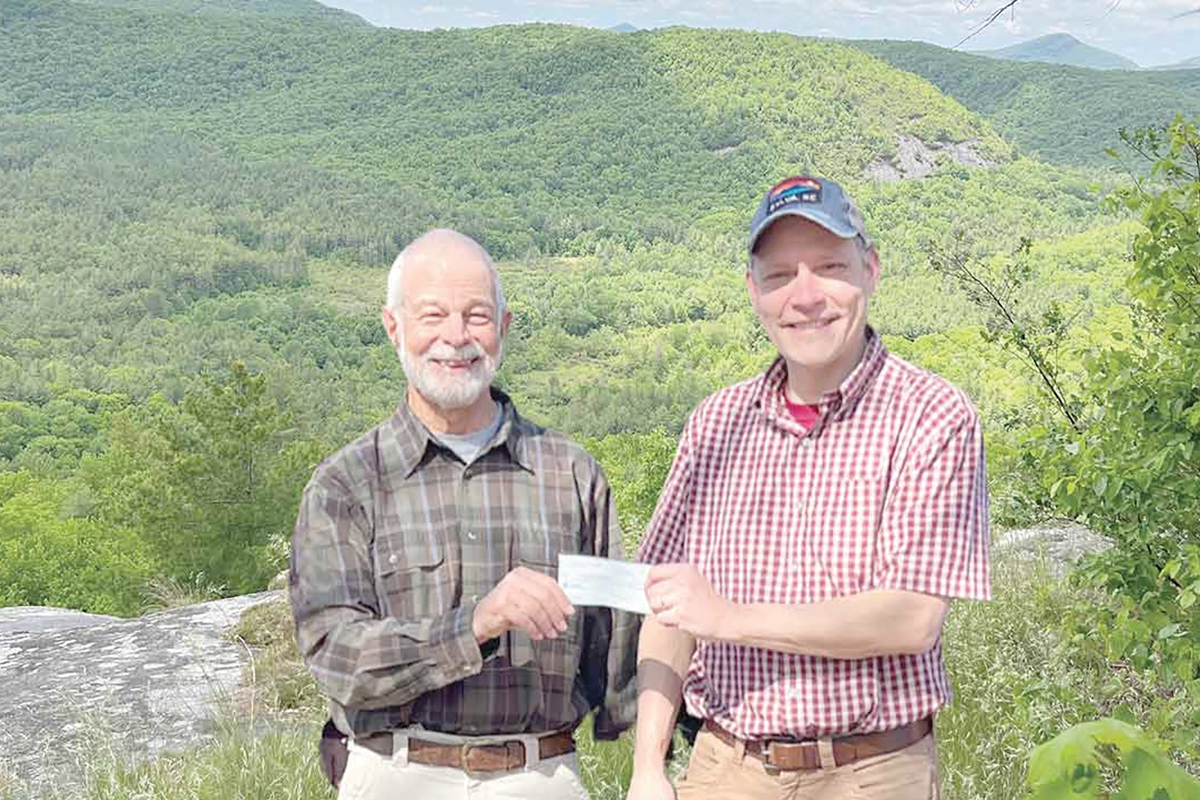 Burt Kornegay (left) hands off the donation to Friends of Panthertown Executive Director Jason Kimenker. 