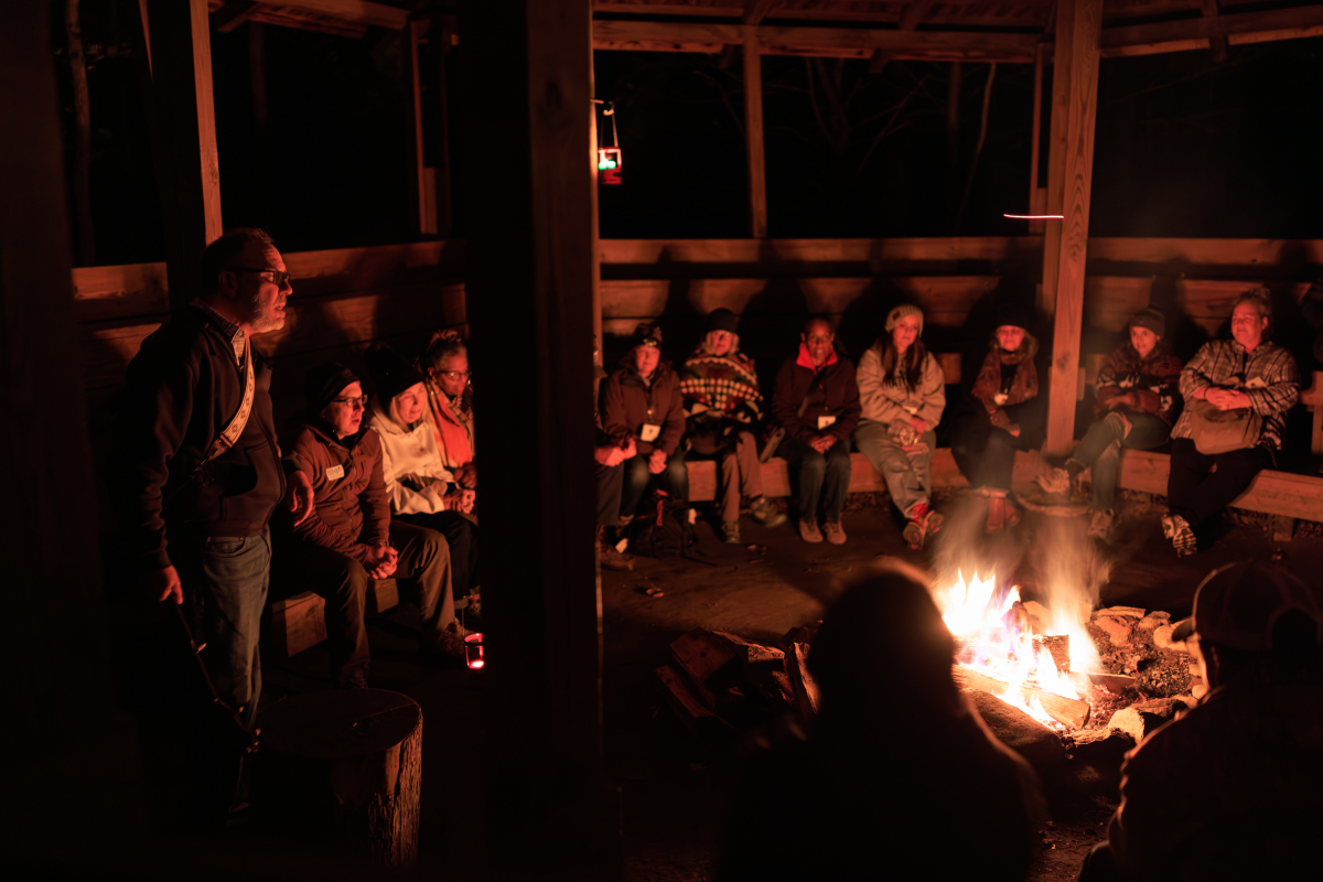 Conference attendees gather around a campfire to celebrate their first evening together during the 2025 Tremont Writers Conference.