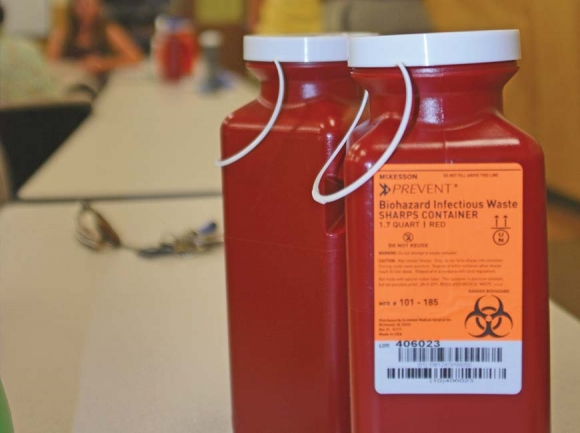 Thick plastic sharps containers sit on a desk during a presentation on needle collection procedures. Cory Vaillancourt photo