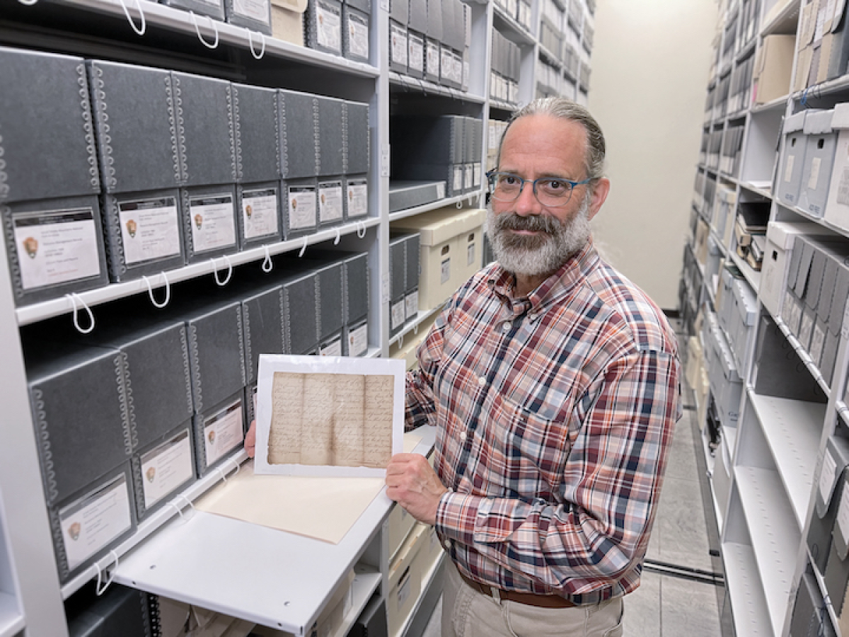 Park librarian-archivist Michael Aday stands in the Great Smoky Mountains National Park archives holding a writ issued in 1786 by James Sevier — son of the governor of Franklin — which instructed the sheriff of Washington County to take Joseph Young into custody in relation to a case of assault and battery brought by Alexander Donny. GSMA photo