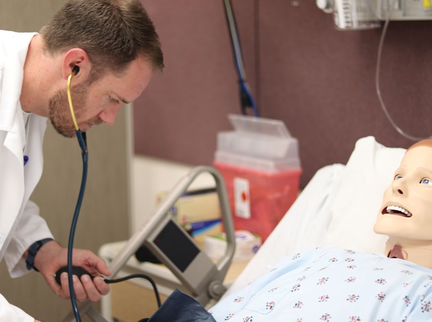 A nursing student at Haywood Community College practices his skills on a                        simulation lab dummy. HCC photo