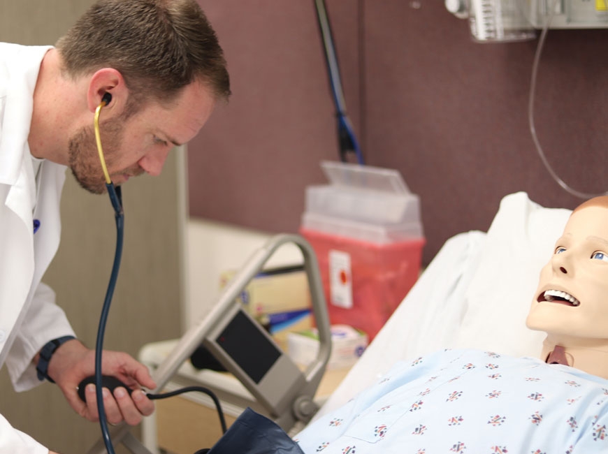 A nursing student at Haywood Community College practices his skills on a                        simulation lab dummy. HCC photo