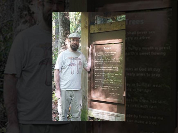 Sign painter Tyler Watras stands with the new sign. Donated photo 