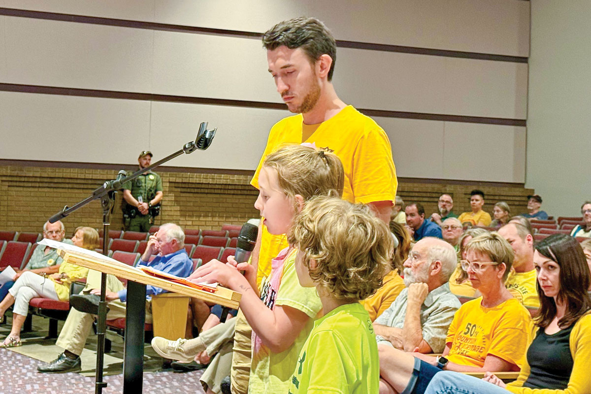 Nine-year-old Evelyn Craig, flanked by her father and brother, spoke in favor of the library. Cory Vaillancourt photo