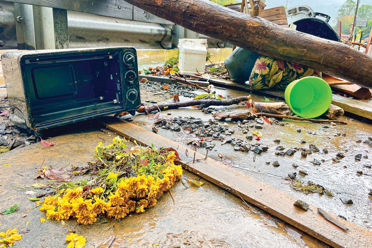 A bouquet of flowers, likely on someone’s porch or kitchen table hours earlier, lies on a Maggie Valley sidewalk alongside other debris from Jonathan Creek. Cory Vaillancourt photo