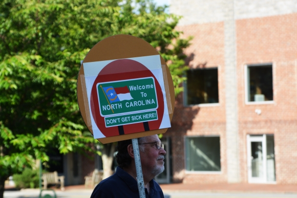 A man holds a sign at a Medicaid expansion rally at the Historic Haywood County Courthouse on June 28, 2019.