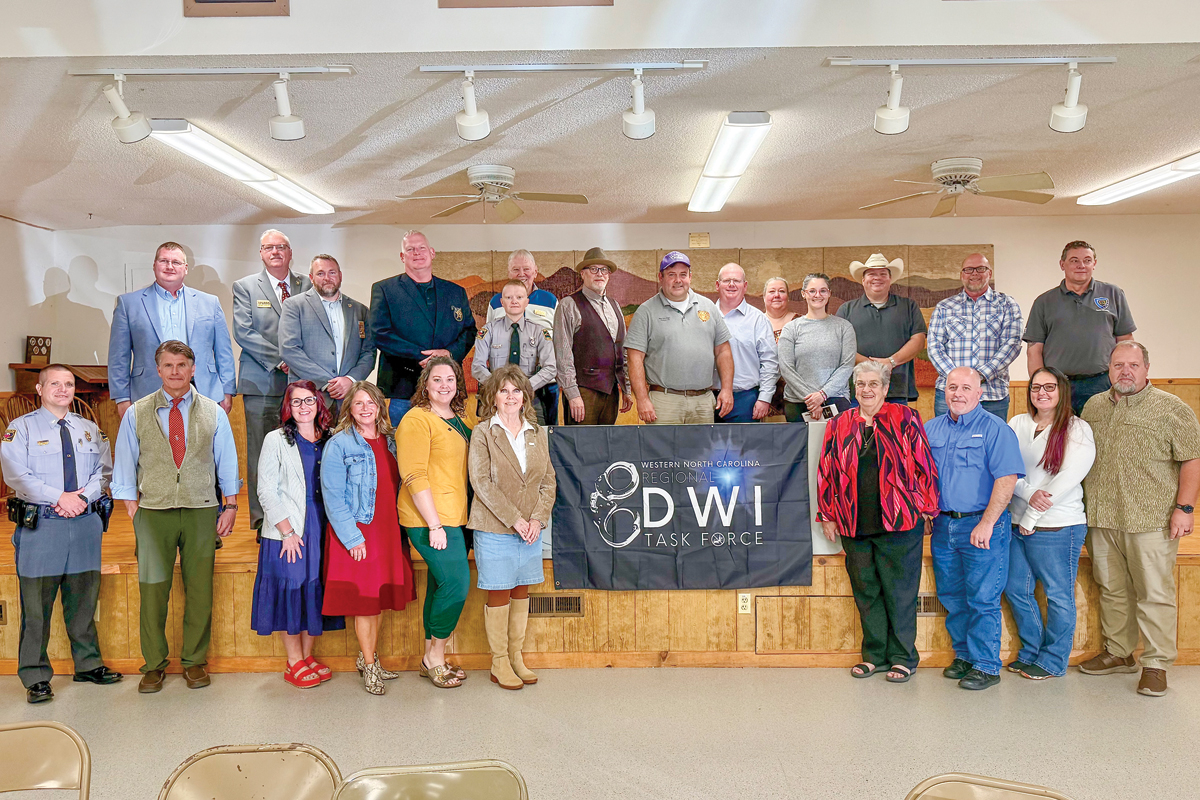 Ellen Pitt (front, left of the banner) brought more than two dozen local leaders together to discuss public safety reform. 