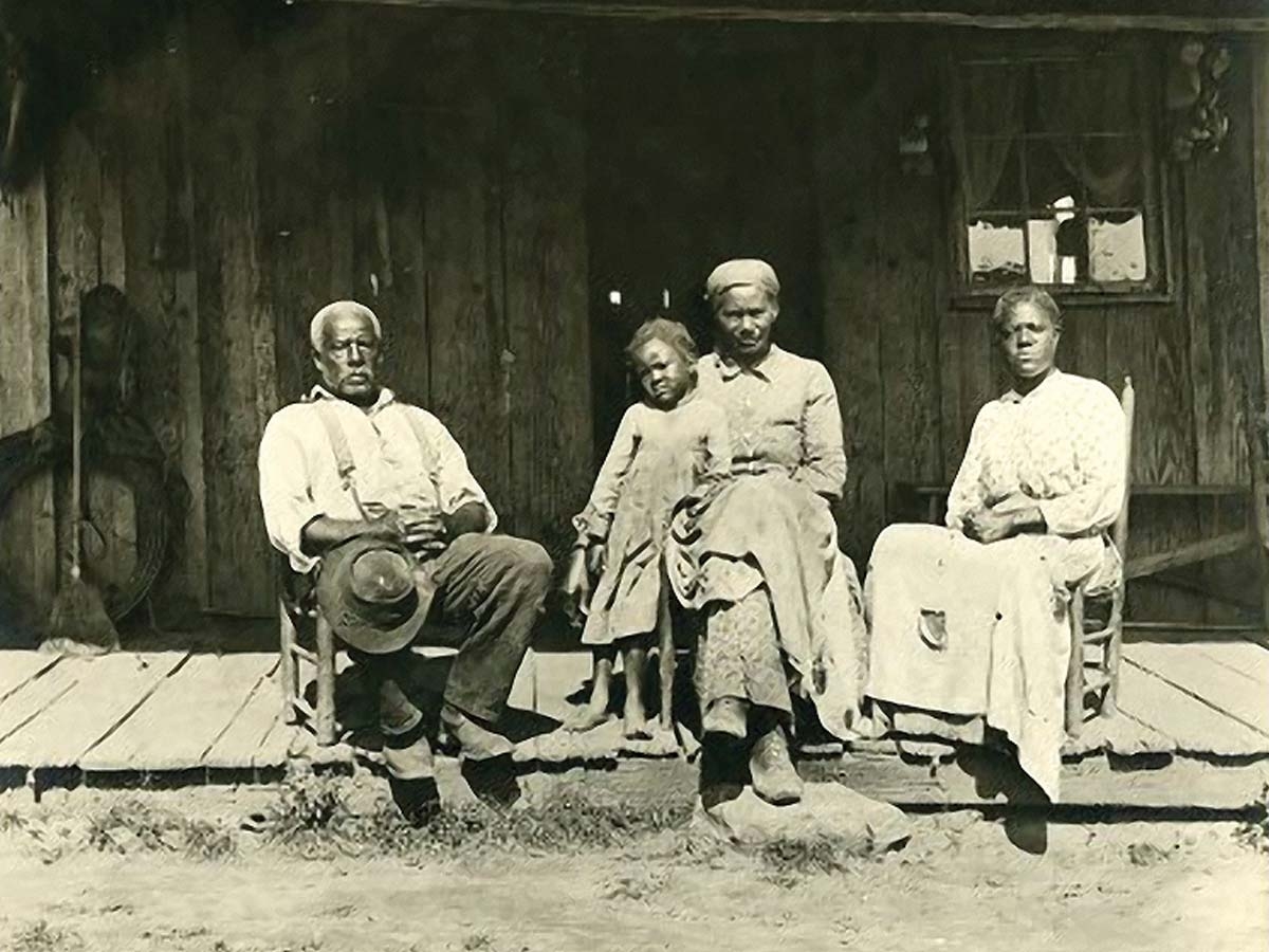 In a photo taken between 1890 and 1903, an African American family sits on a front porch in the Great Smokies region.  W.O. Garner Photograph Collection