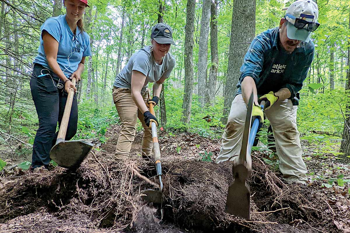 A trailbuilding crew pulls back a mat of leaves and roots. Pat Barcas photo
