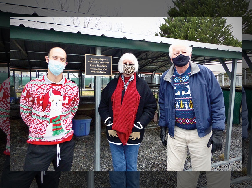 Sarge’s staff and board members met Dec. 17 to dedicate a memorial plaque to long-time Sarge’s supporter, Gary Smith. Pictured, from left, are Jed Lambert, Sarge’s board president; Sarah Jane League, Smith’s wife; and Steve Hewitt, Sarge’s treasurer. Carol Viau photo