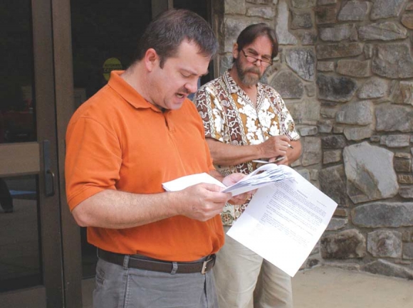 In this 2009 photo, Rick Boyd conducts a foreclosure sale of two large tracts owned by developer Legasus outside the Jackson County courthouse while concerned citizen Thomas Crowe follows along.