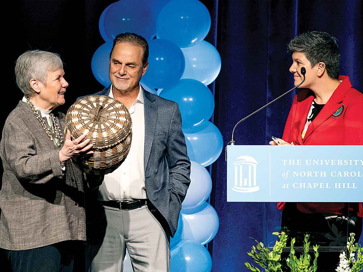 Gladys Cardiff (left), daughter of Henry Owl, receives a gift from Eastern Band of Cherokee Indians Chief of Staff Ashleigh Stephens while sharing the stage with Tribal Council Rep. Boyd Owle at the dedication ceremony May 13. Jon Gardiner/UNC-Chapel Hill photo