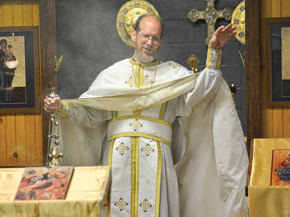 Father Anthony Perkins (above) conducts a Christmas service on Jan. 7, and later baptized Dakota Holbrook (below). Cory Vaillancourt photos