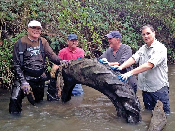 Volunteers haul a discarded tire out of a creek. Donated photo