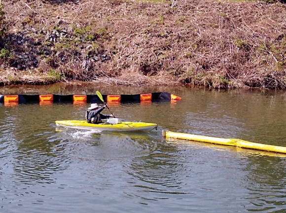 Jim Pearson removes the temporary yellow containment boom to make way for the new booms. Donated photo